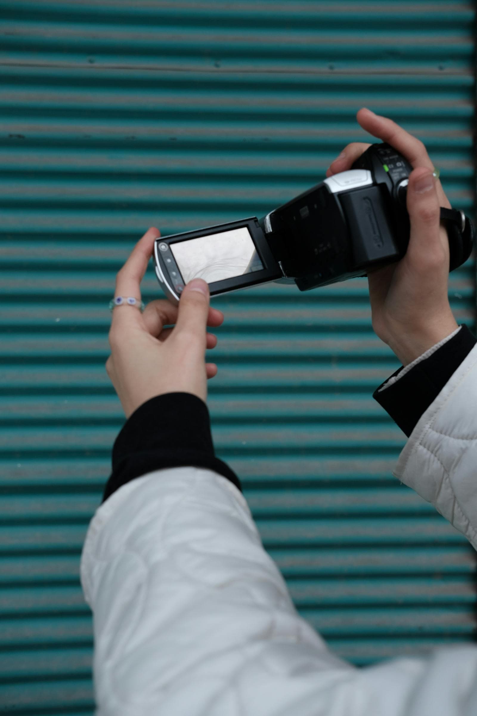 Close-up of a retro camcorder held against a teal striped backdrop